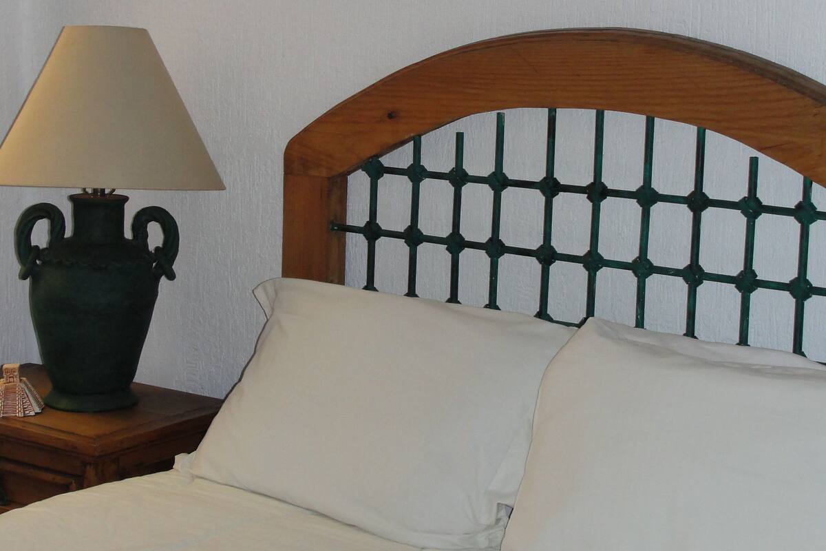 Ein Bett mit Holz-Kopfteil, einer Nachttischlampe und einer Wanddekoration.