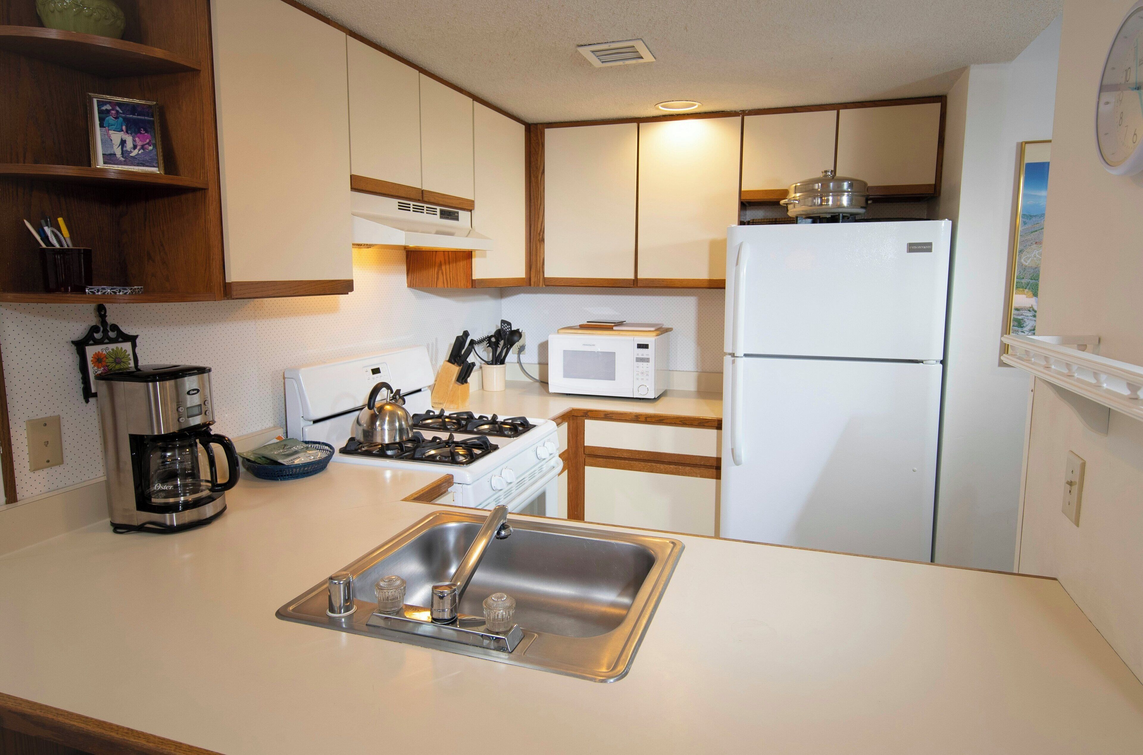 Una cocina compacta equipada con fregadero, estufa, microondas y refrigerador.