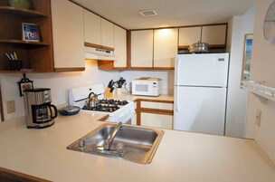 Una cocina compacta equipada con fregadero, estufa, microondas y refrigerador.