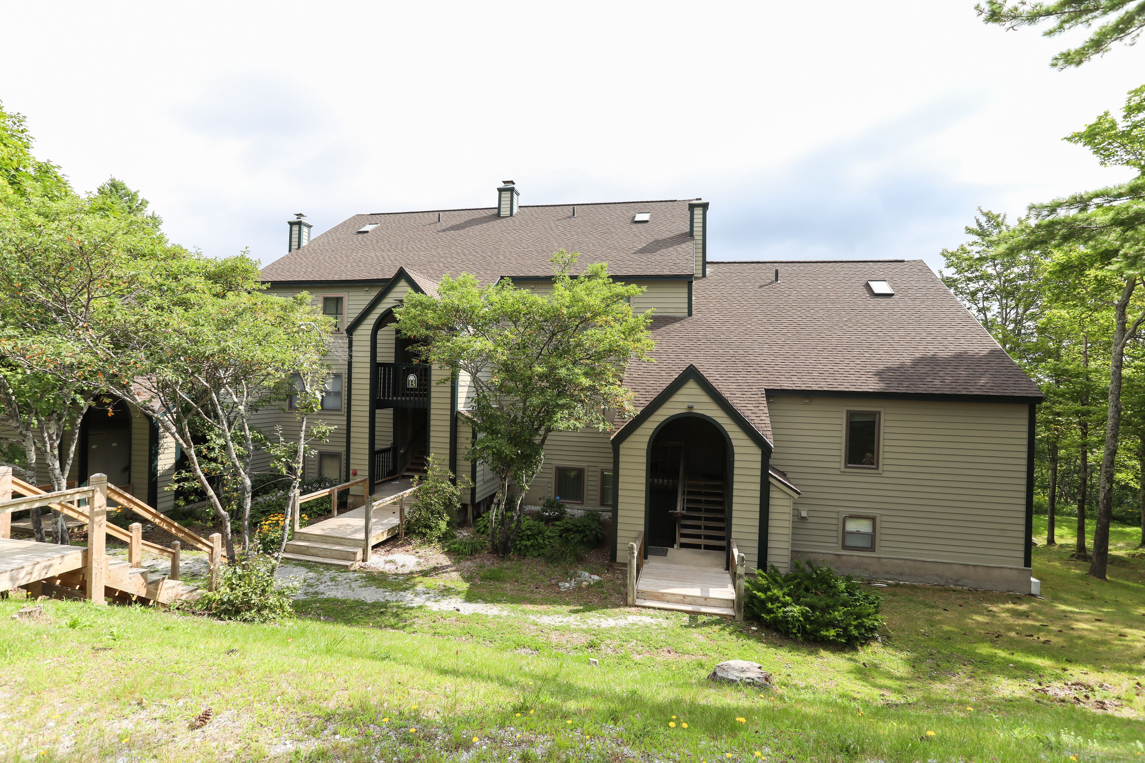 A two-story house with a front porch, a staircase, and a small garden area.