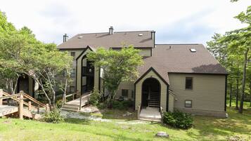 A two-story house with a front porch, a staircase, and a small garden area.
