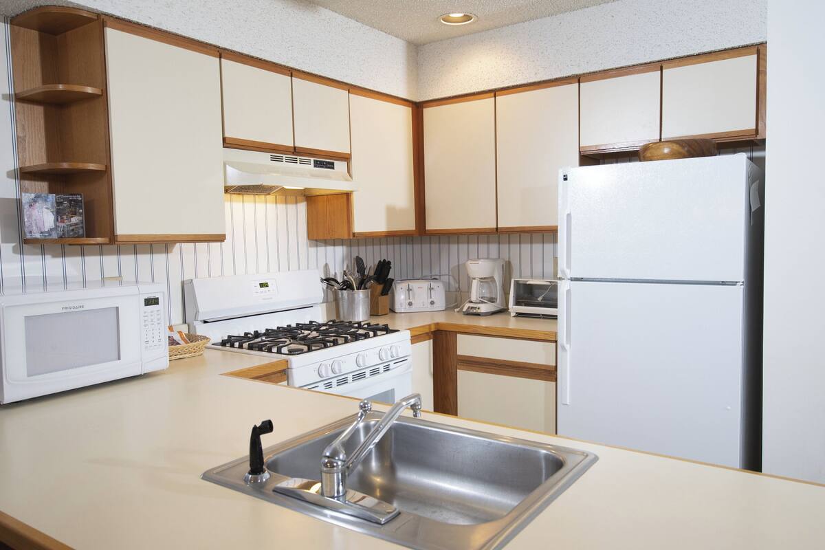 A kitchen with a microwave, stove, sink, and refrigerator.