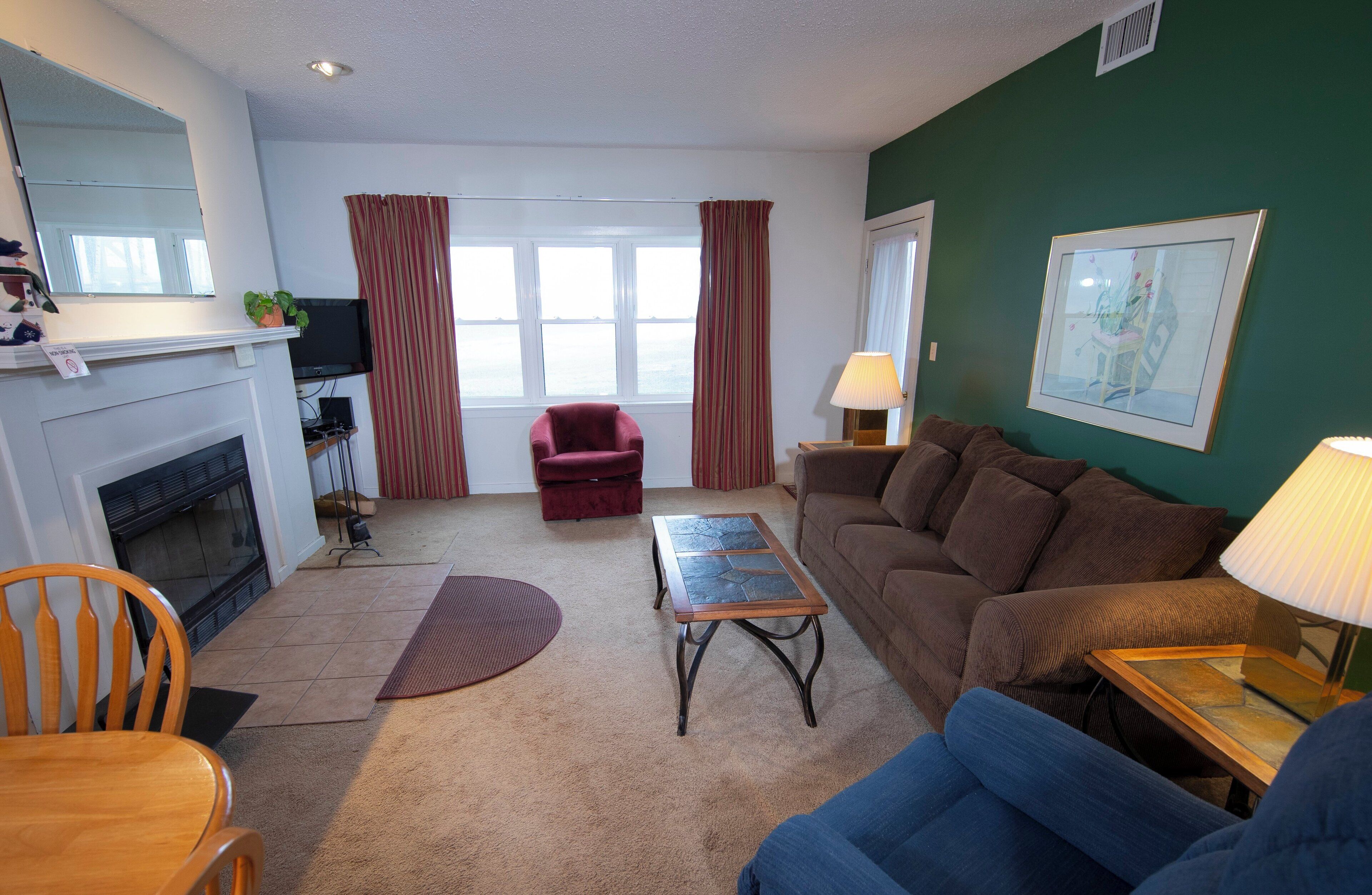 A living room with a fireplace, a couch, a coffee table, and a television.