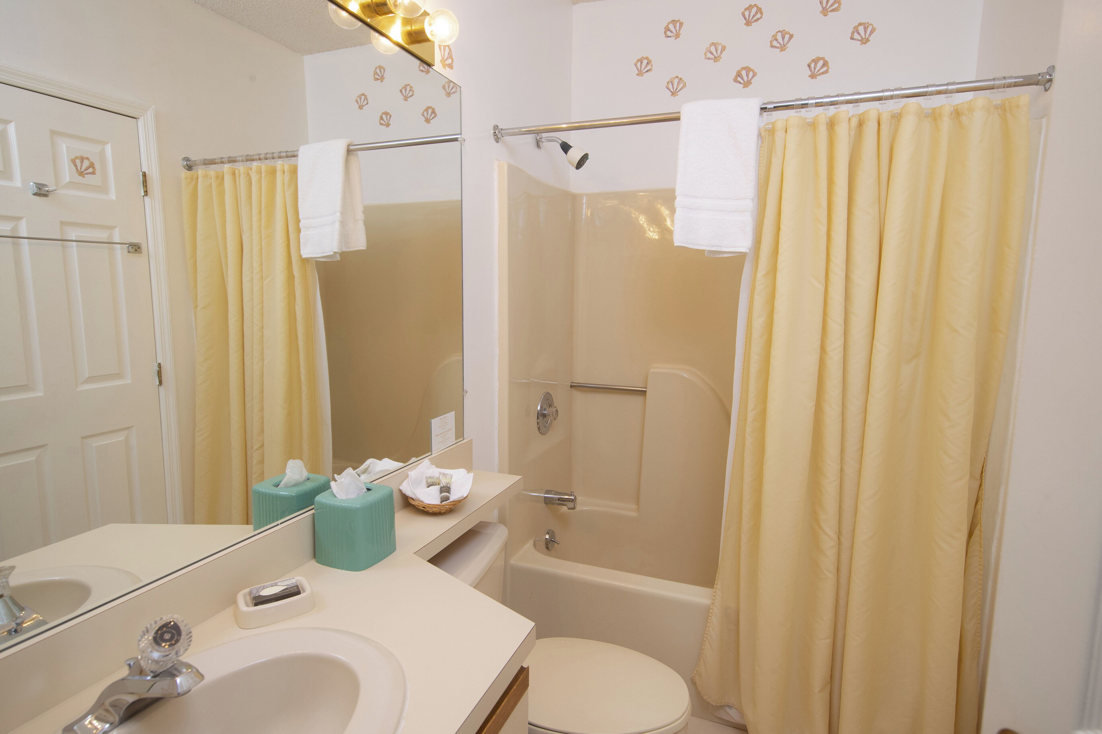A bathroom with a sink, mirror, toilet, and shower area.