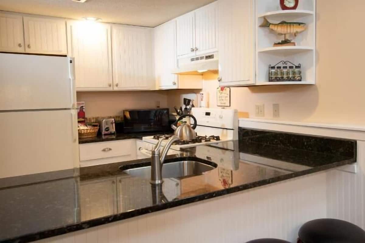 A kitchen with white cabinets, a stainless steel sink, a microwave, and a toaster.