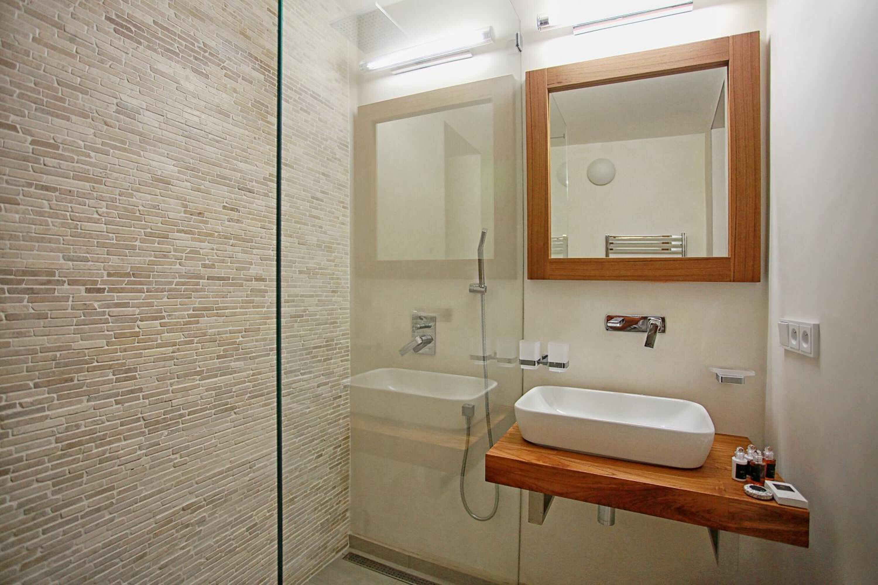 Une salle de bain moderne avec une douche à parois de verre, un meuble-lavabo en bois et un grand miroir.