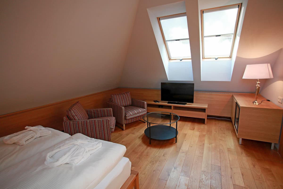 Una habitación con cama, televisión, escritorio, silla y lámpara.