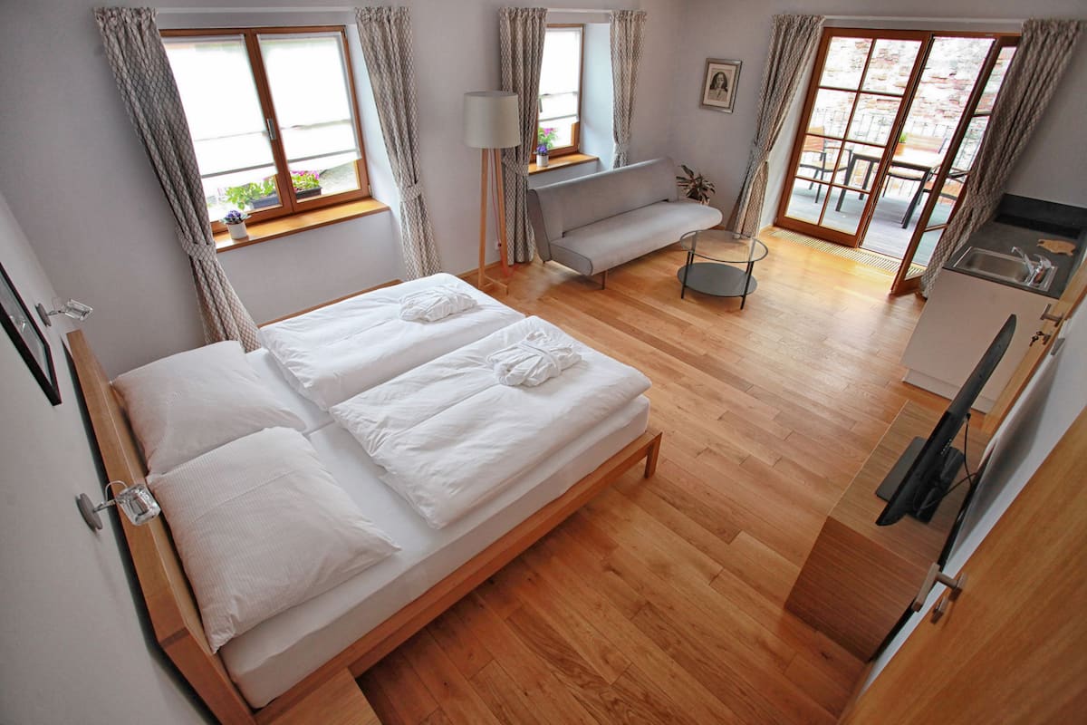 Un dormitorio con dos camas, un sofá, una mesita y una kitchenette.