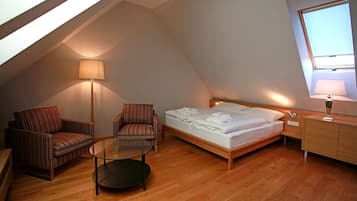 Una habitación acogedora con una cama, dos sillones a rayas, una mesita y una lámpara.