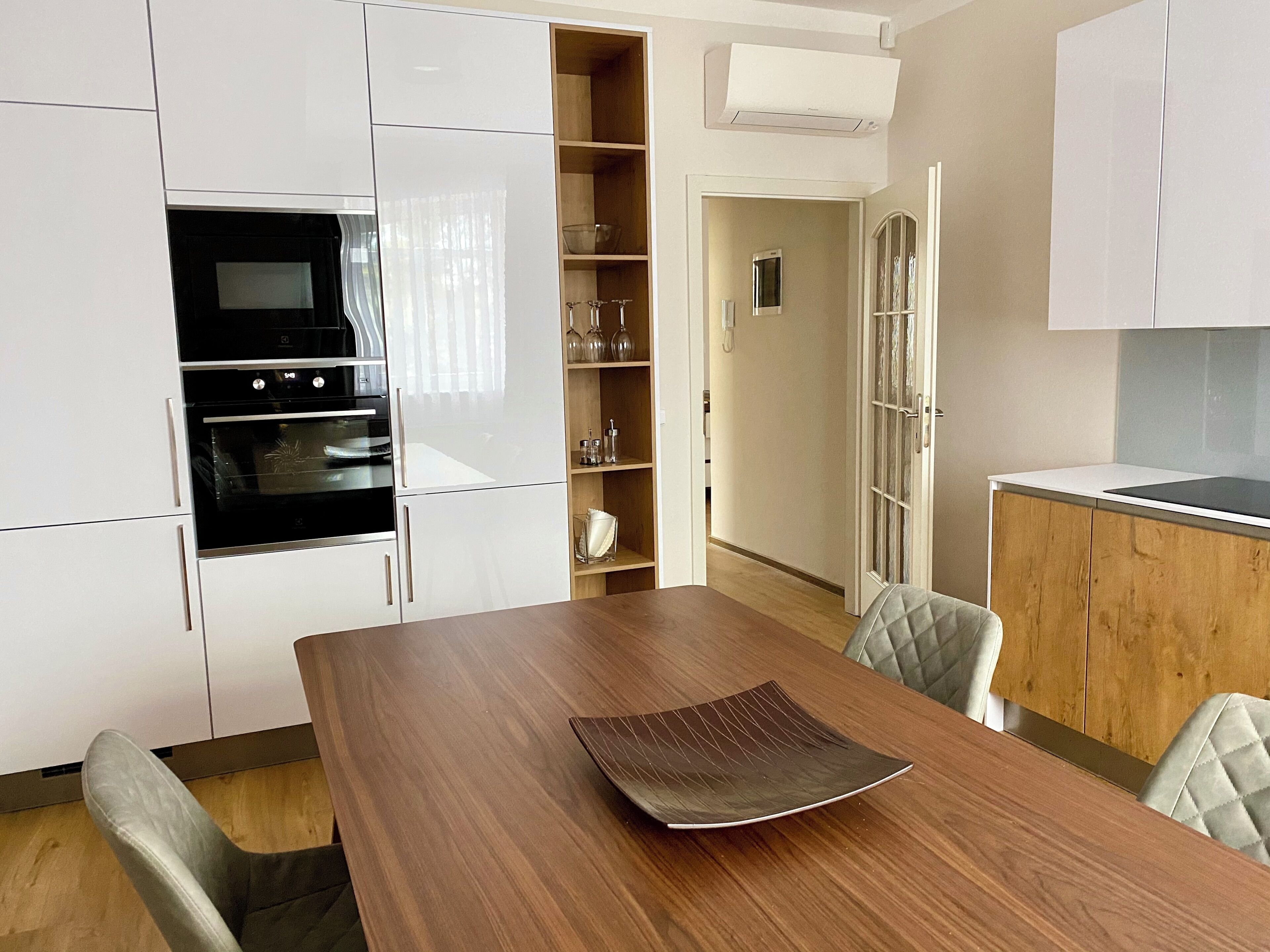 Una cocina moderna con armarios blancos, horno y una mesa de comedor con un mantel individual.