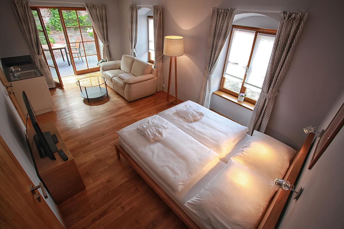 Un dormitorio con cama, sofá, lámpara y vista al exterior.