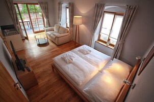 Quarto com cama, sofá, luminária e vista para o exterior.