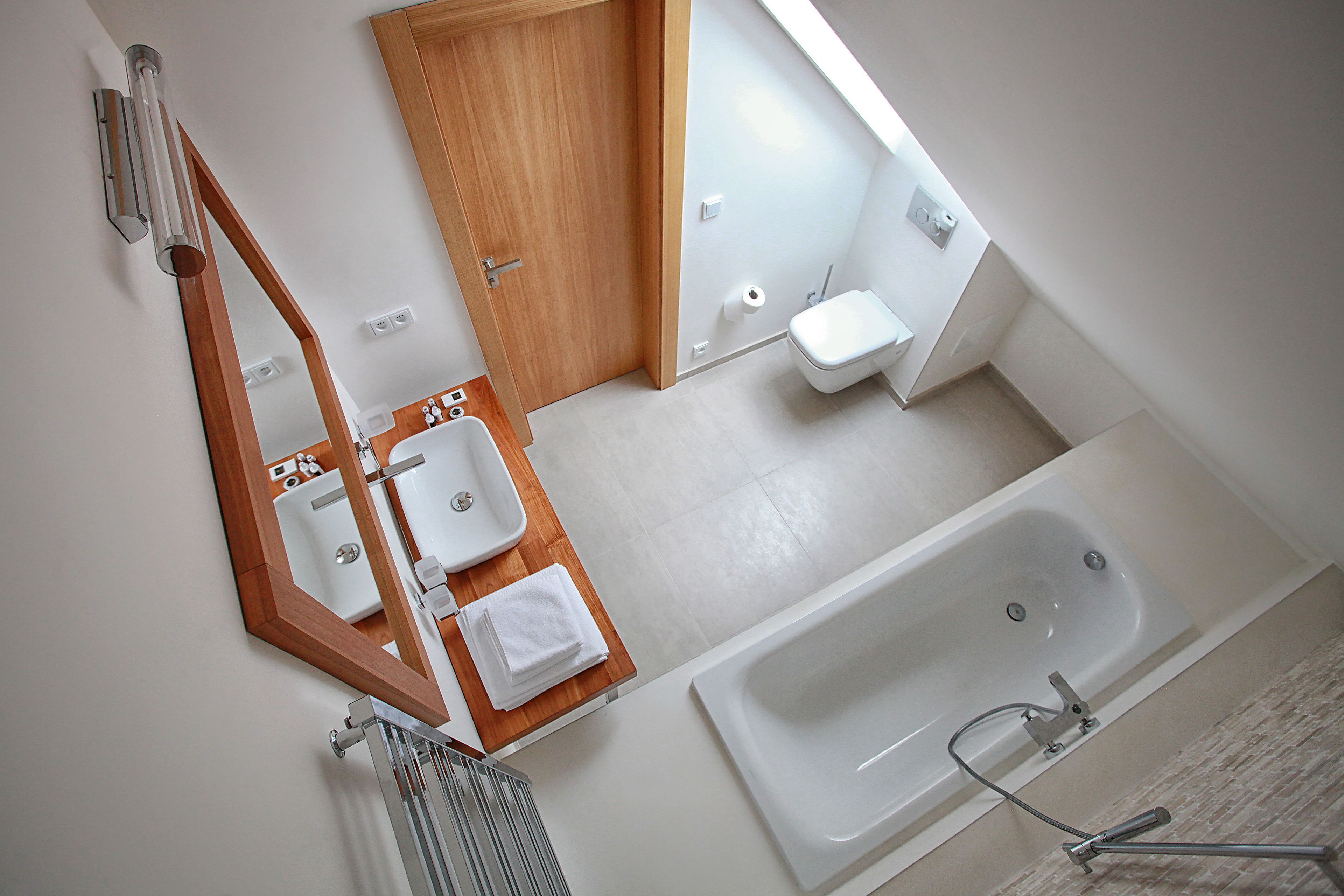 Un baño moderno con tocador de madera, una bañera grande y un inodoro.