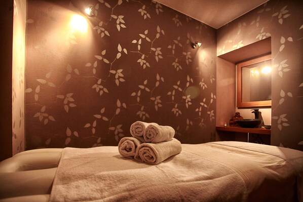 Un baño con cama, toallas, lavamanos y espejo.