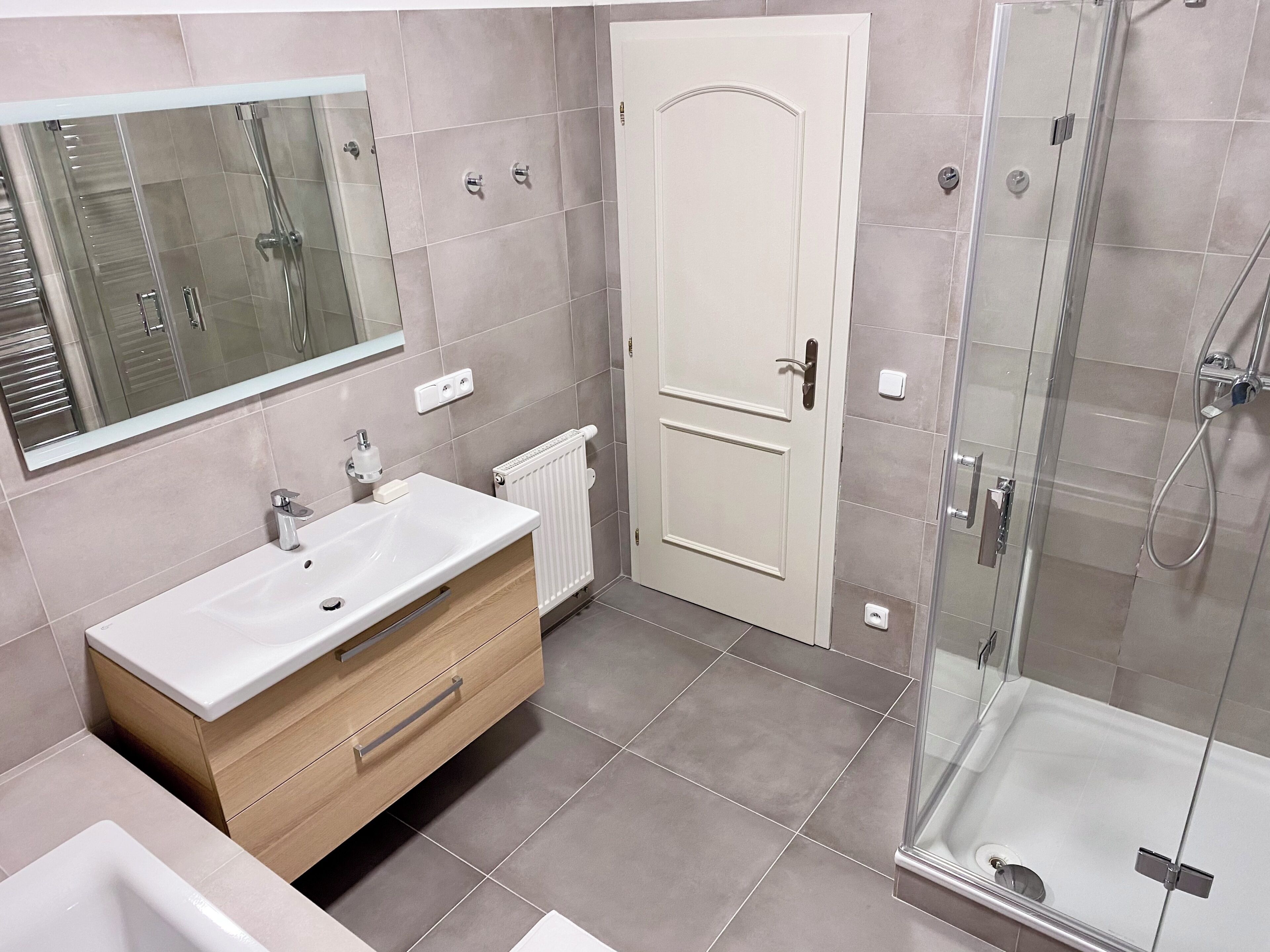 A modern bathroom with a large mirror, a sink, a toilet, and a shower area.