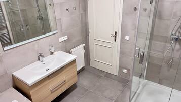 A modern bathroom with a large mirror, a sink, a toilet, and a shower area.