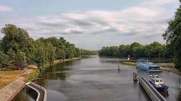 Un río con esclusas, una embarcación azul amarrada y un puente al fondo.