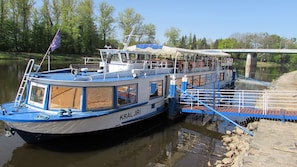 A riverboat docked at a pier with a covered deck area and a lifebuoy visible. - Penzion Dobré časy (Podebrady)