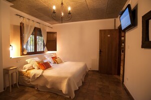 Un dormitorio con cama, televisor montado en la pared y ventana con cortinas.