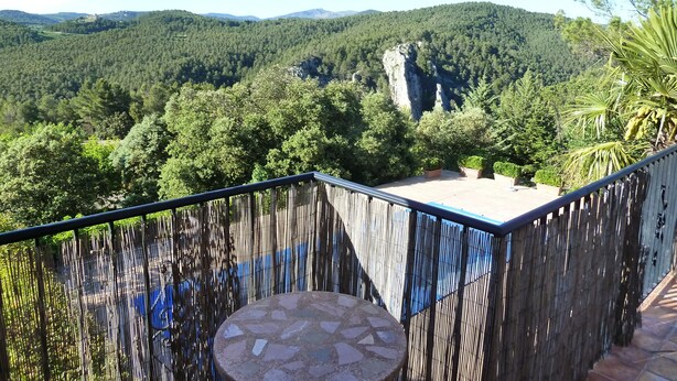A balcony with a stone table, bamboo fence, and a view of a forested mountain range. - Casa Bons Aires - Adults Only (Alcoy)