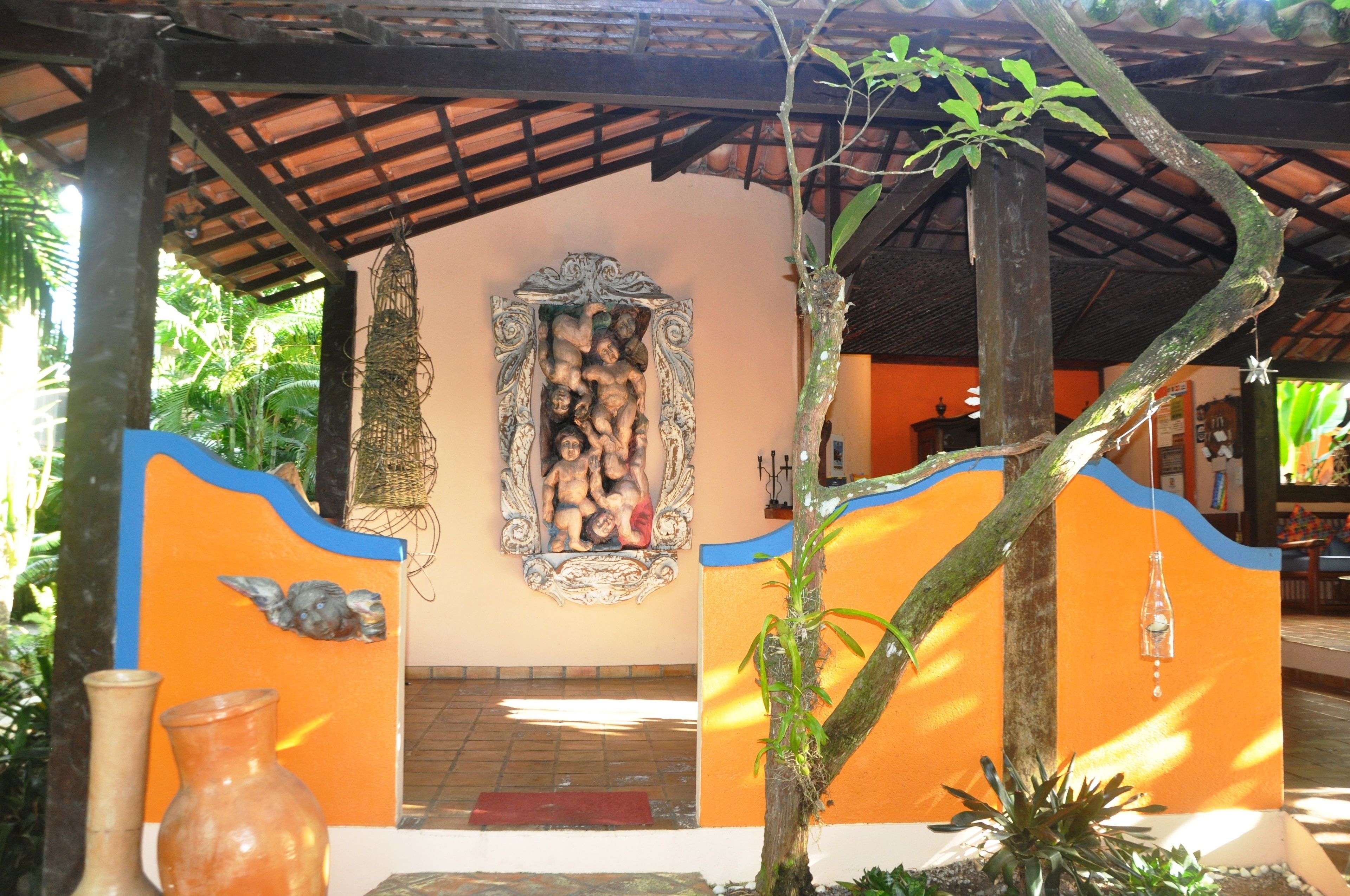 A covered outdoor area with a decorative wall, a hanging basket, and a tree.