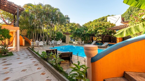 A pool area with lounge chairs and a staircase leading to a covered area. - Pousada Bemvirá (Porto Seguro)