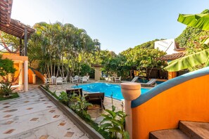 A pool area with lounge chairs and a staircase leading to a covered area. - Pousada Bemvirá (Porto Seguro)