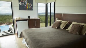 Een slaapkamer met een groot bed, een bureau met een computer en uitzicht op het landschap.