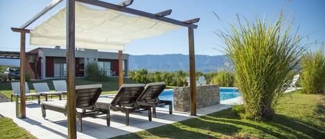 Une terrasse avec des sièges extérieurs, une piscine et une vue sur les montagnes.