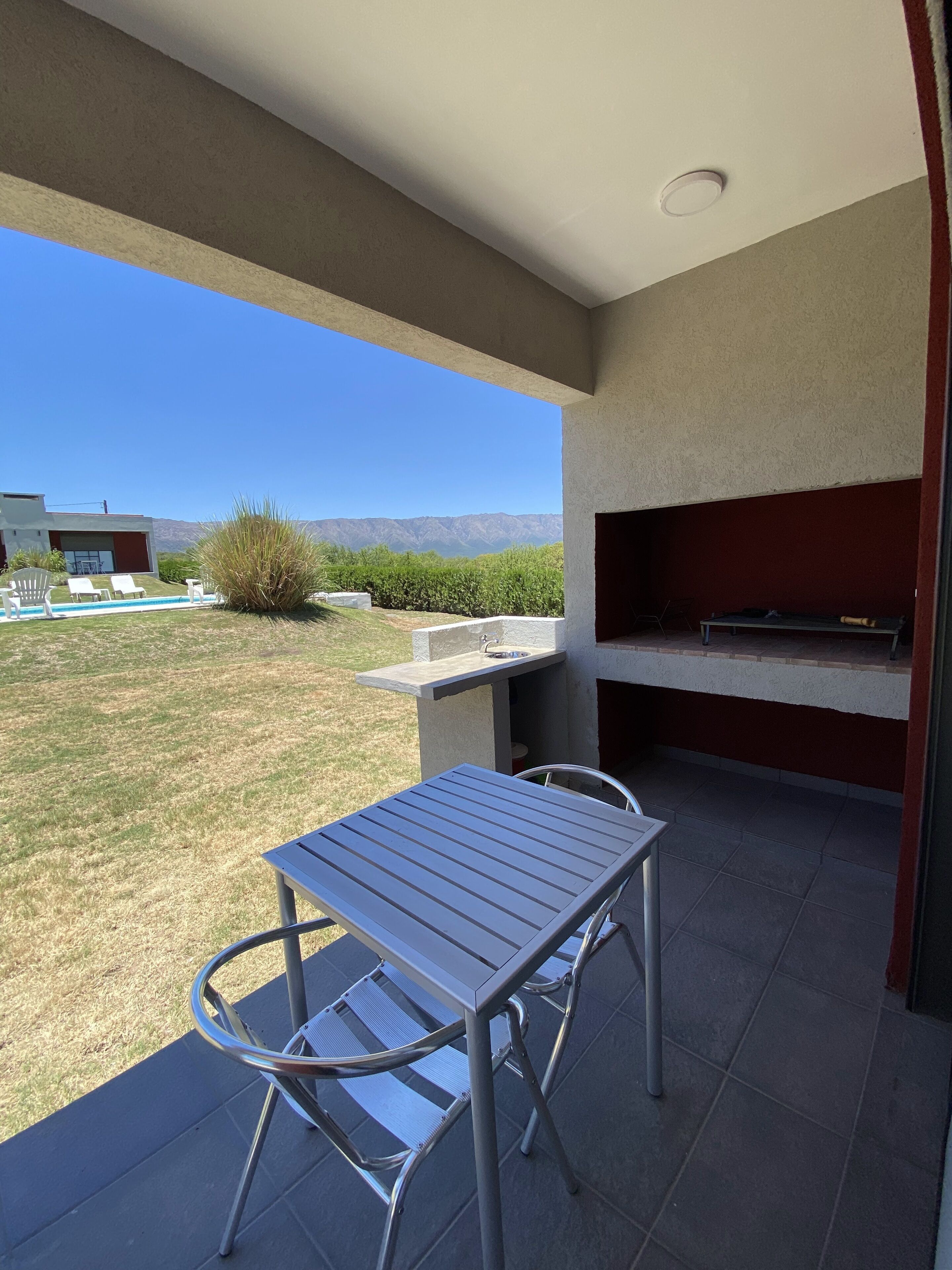 Un patio al aire libre con mesa y sillas, una parrilla de barbacoa y vistas a las montañas.