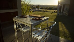 Een terras met een tafel, metalen stoelen, een houten snijplank en een mes.