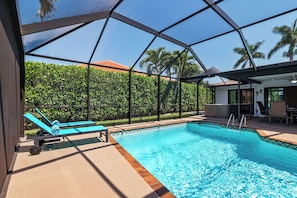 An indoor swimming pool with lounge chairs and a covered patio area. - Villa Turquoise Coast (Cape Coral)