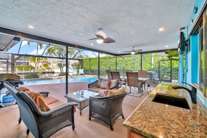 A covered outdoor area with wicker furniture, a pool, and a bar. - Villa Turquoise Coast (Cape Coral)