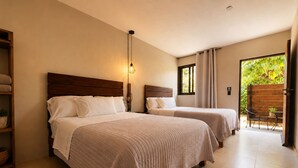 Une chambre avec deux lits, une lampe de chevet, une fenêtre avec des rideaux, une chaise et une vue sur la verdure à l’extérieur.