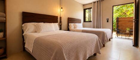 Un dormitorio con dos camas, una lámpara de noche, una ventana con cortinas, una silla y vistas al exterior con vegetación.