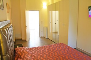 Ein Schlafzimmer mit einem Bett, einem Kleiderschrank und einer Tür zu einem anderen Raum.