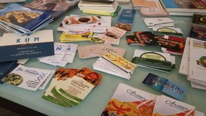 A table covered with various printed materials, including brochures and pamphlets, likely related to local attractions or services. - Arcona (Carpignano Salentino)