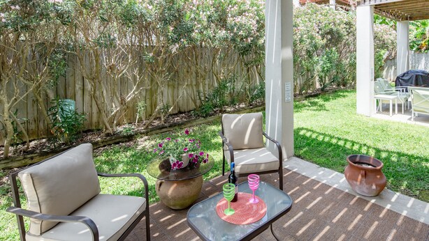 Une terrasse extérieure avec deux chaises, une table et un pot de fleurs.