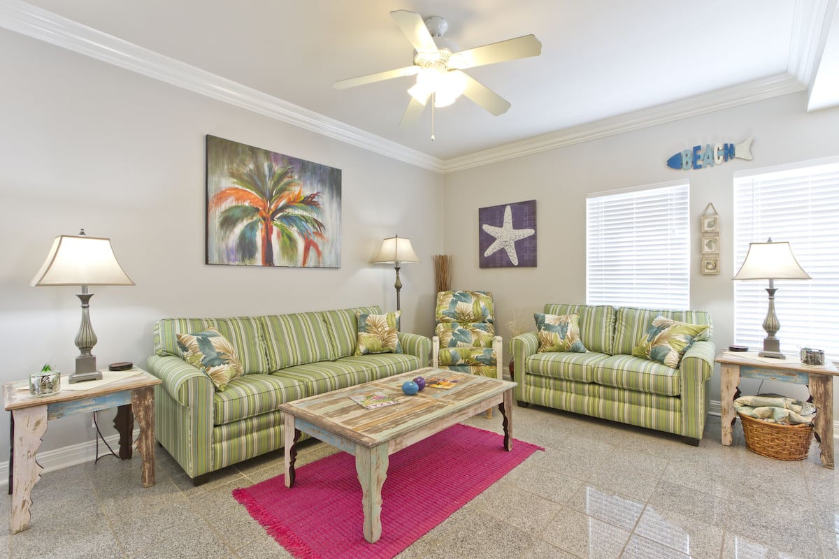 A living room with two striped sofas, a coffee table, and a ceiling fan.