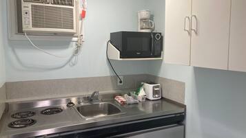 Una cocina con estufa, fregadero, microondas y cafetera.