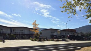 A hotel with a balcony, a sandy area in front, and a mountain in the background. - Golden Sands Resort Motel (Penticton)