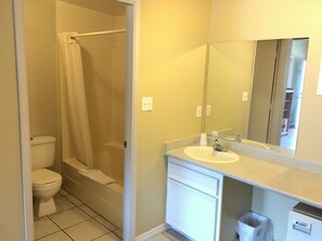 A bathroom with a toilet, bathtub, and sink. - Golden Sands Resort Motel (Penticton)