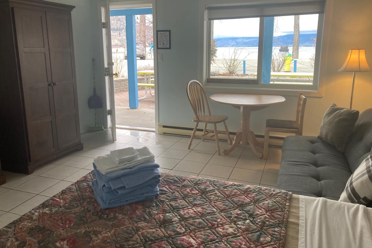 Een kamer met een bed, een stoel, een tafel, uitzicht op de omgeving en een deur naar buiten.