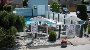 A pool area with a sign indicating 'ALL TRAFFIC ONE WAY MAXIMUM 5 Km/H' and 'CAUTION CHILDREN PETS & DUCKS'. - Golden Sands Resort Motel (Penticton)