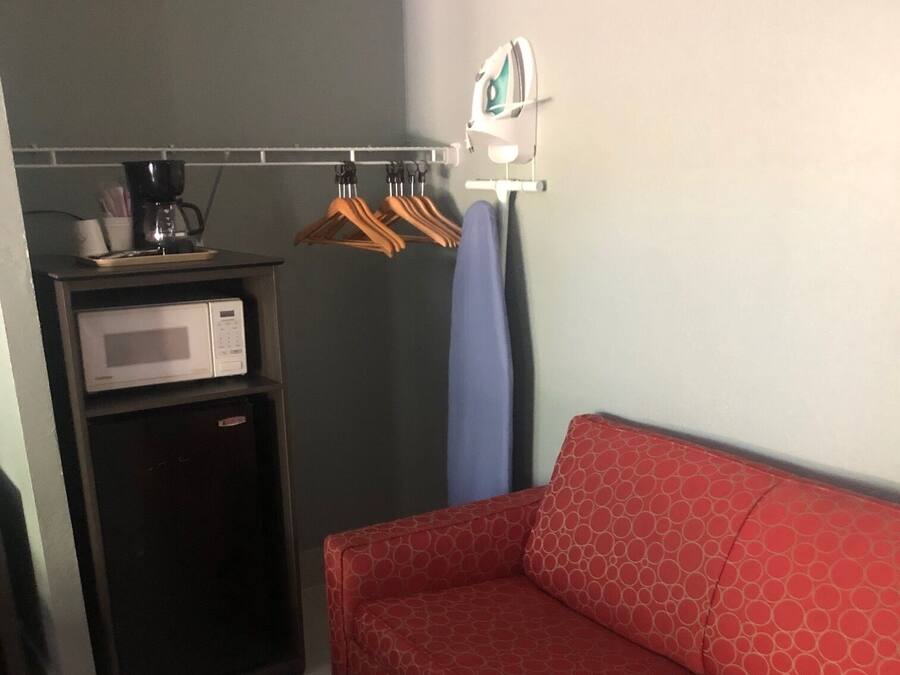 Een compacte kamer met een rode bank, een magnetron en een kleine koelkast.