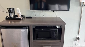 Un angolo cottura compatto dotato di frigorifero, forno a microonde e macchina del caffè.