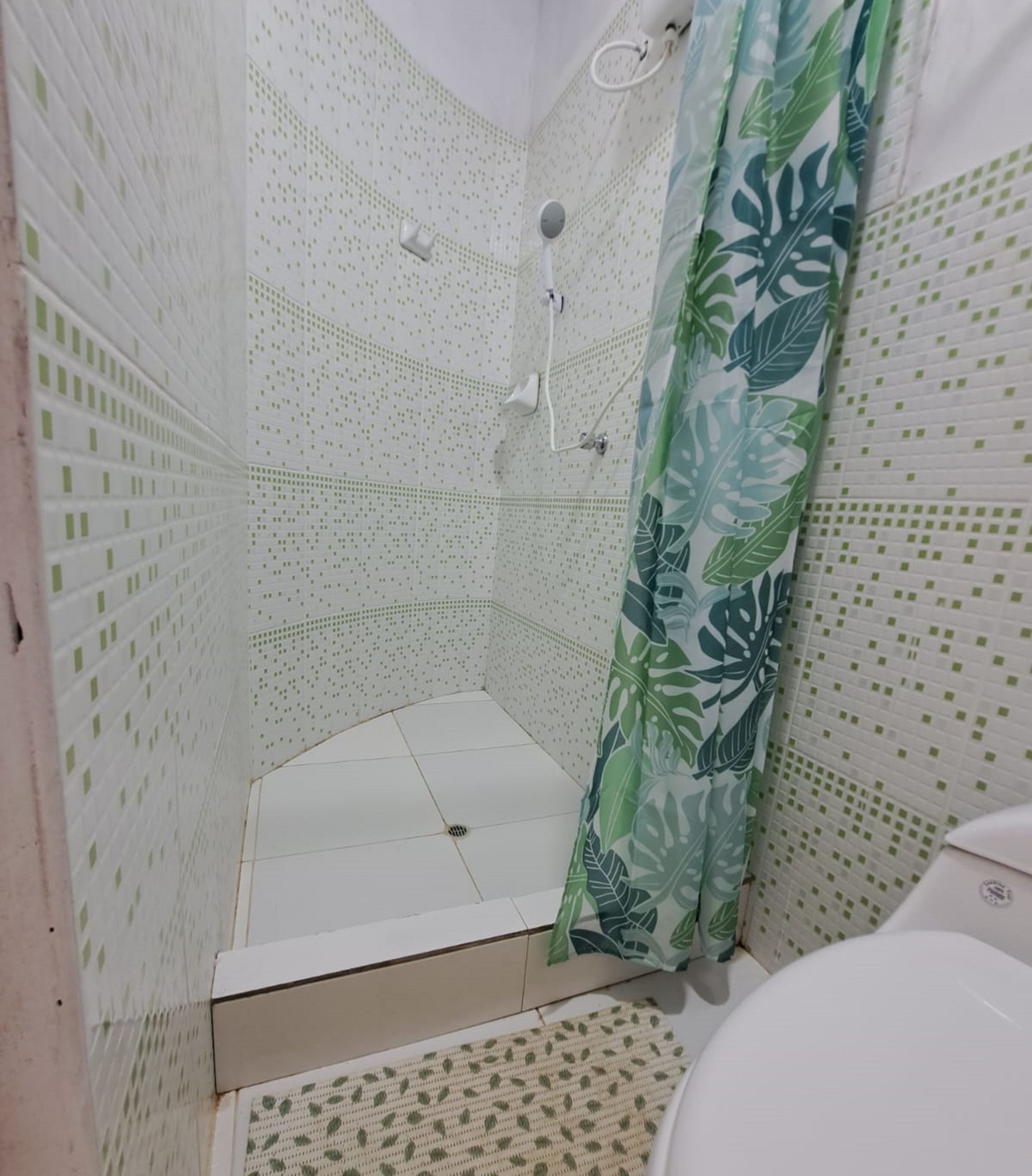 Un baño con ducha, inodoro y suelo estampado.