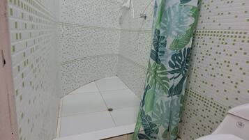 Un baño con ducha, inodoro y suelo estampado.