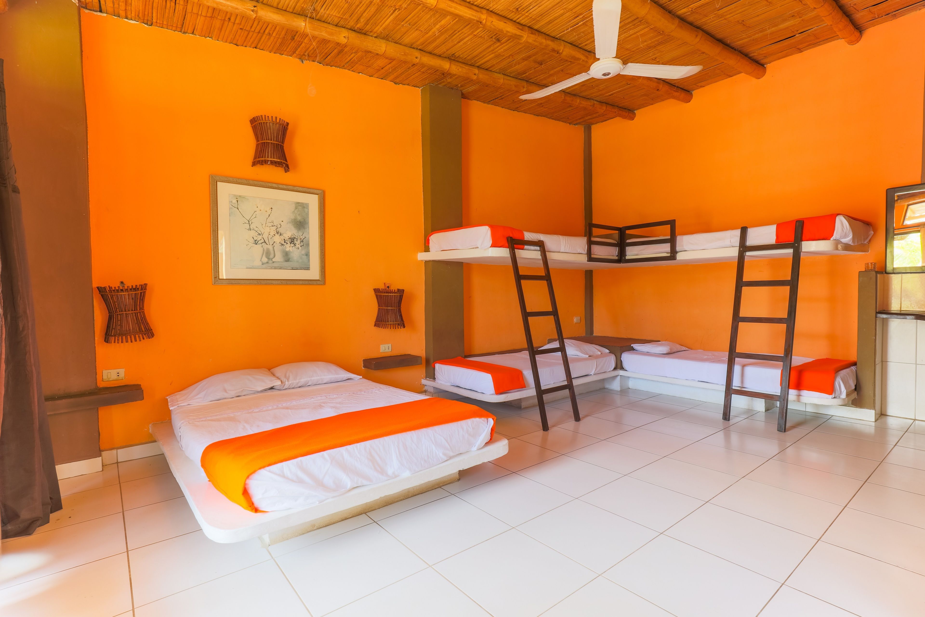 Una habitación con tres literas, un ventilador de techo y un cuadro en la pared.