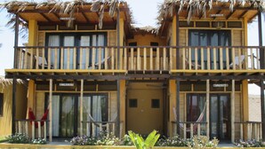 Un edificio de dos pisos con un balcón de madera, un techo de paja y un letrero que dice "CARACOLITO DE MAR".